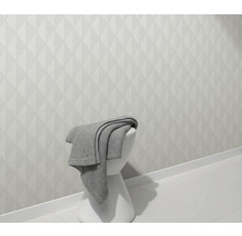 Ljus vägg med geometriskt mönster och pall med filt