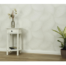 Miljöbild med mönstrad tapet, sängbord och krukväxt.