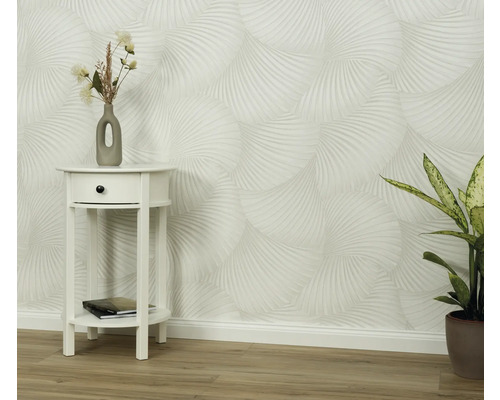 Miljöbild med mönstrad tapet, sängbord och krukväxt.