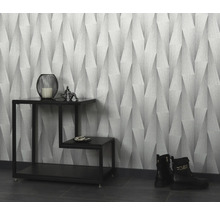 Rumsöversikt med mönstrad tapet, dekorationer på ett sidobord och stövlar