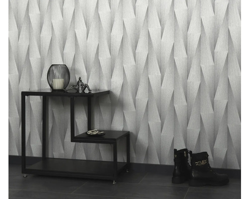 Rumsöversikt med mönstrad tapet, dekorationer på ett sidobord och stövlar