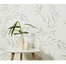 Dekorativ tapet med bladmönster, kombinerat med ett bord och krukväxter i vaser.