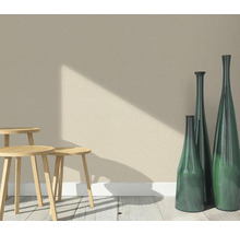 Scen med tre träpallar och tre smala dekorativa vaser på ett trägolv framför en vägg