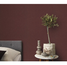 Sovrum med säng, sängbord och dekorativ väggtapet för en mysig atmosfär.