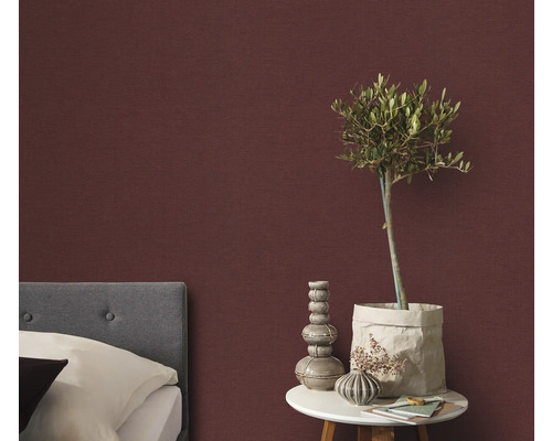 Sovrum med säng, sängbord och dekorativ väggtapet för en mysig atmosfär.