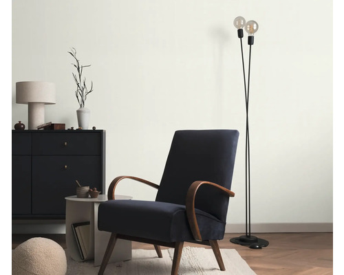 Vardagsrum med fåtölj, golvlampa och byrå för en mysig atmosfär.