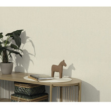 Vardagsrum med en strukturerad tapet, dekorerad med en växt, en hästfigur och böcker på ett bord