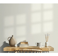 Ljust arbetsrum med skrivbord, bokstapel, vaser och en mugg