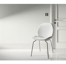 Miljöbild med en stol med metallben och vadderad sits i ett ljust rum.