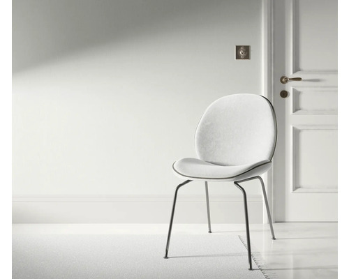 Miljöbild med en stol med metallben och vadderad sits i ett ljust rum.