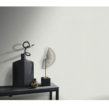 Närbild av en strukturerad vägg med dekorativa föremål på en hylla.