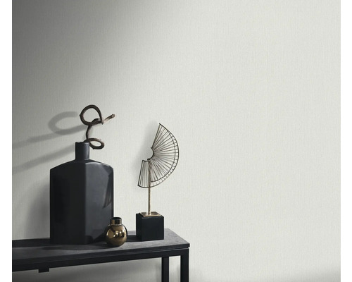 Närbild av en strukturerad vägg med dekorativa föremål på en hylla.