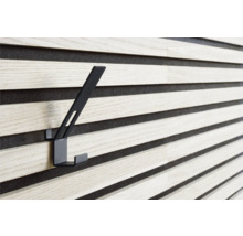 Svart klädkrok på en träpanelvägg