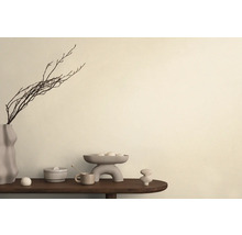 Dekorativt arrangemang med vas, grenar, skål och keramikobjekt på ett bord.