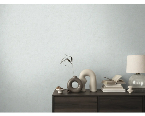 Vardagsrum med mönstrad tapet och byrå med dekorativa element.