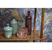 Dekorativa vaser och glasföremål på en trähylla framför en mönstrad tapet