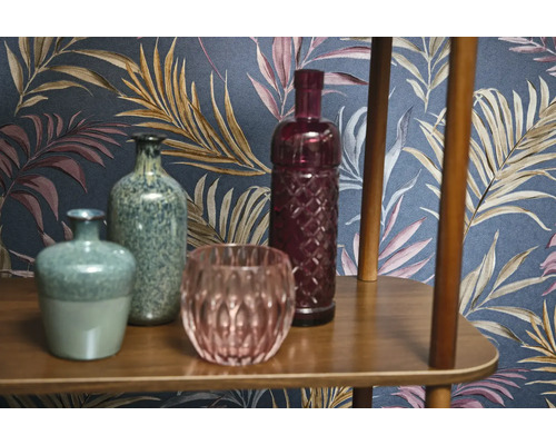 Dekorativa vaser och glasföremål på en trähylla framför en mönstrad tapet