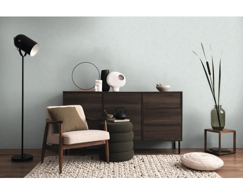 Vardagsrum med byrå, fåtölj, golvlampa och dekorativa element för en mysig atmosfär