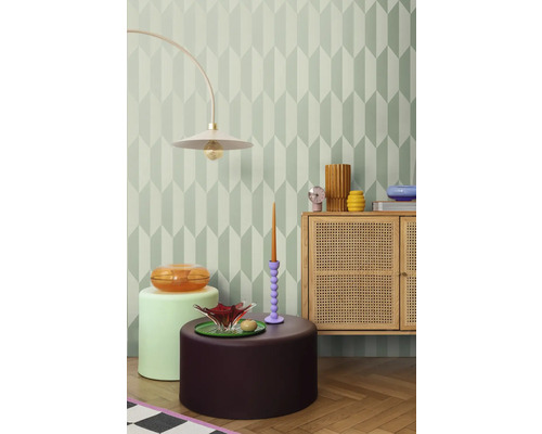 Dekorativt rum med geometrisk tapet, golvlampa, byrå och sidobord.