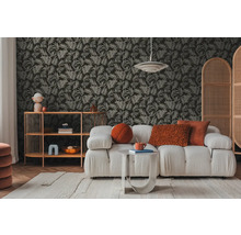 Vardagsrum med soffa, sidobord och hylla framför en tapet med bladmönster