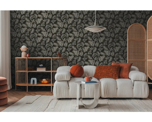 Vardagsrum med soffa, sidobord och hylla framför en tapet med bladmönster