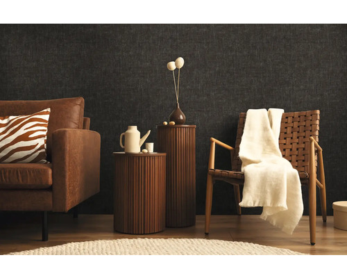 Vardagsrum med soffa, fåtölj och sidobord framför en mörk vägg