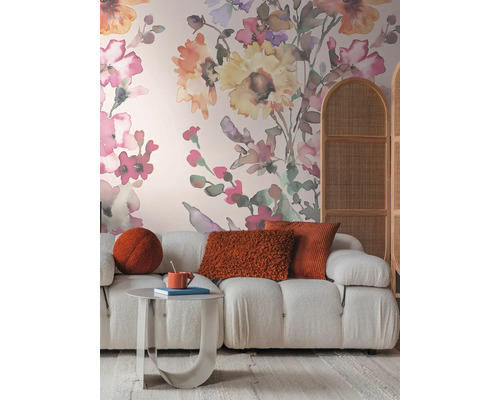 Vardagsrum med soffa, bord, kuddar och blomstertapet för en mysig atmosfär