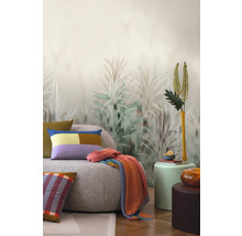 Vardagsrum med soffa, kuddar, filt och tapet med växtmotiv