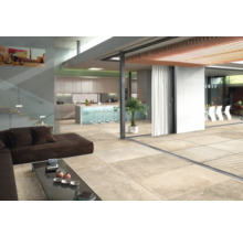 Ljust vardagsrum med klinkergolv, soffa, bord och köksdel.