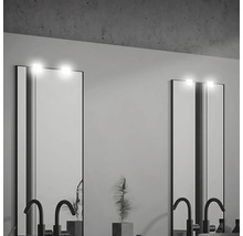 Två belysta speglar med armaturer i ett badrum.