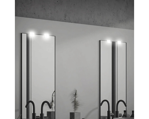 Två belysta speglar med armaturer i ett badrum.