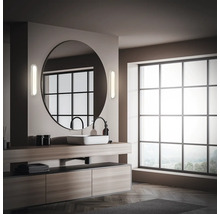 Modernt badrum med stor spegel, tvättställ och fönster.