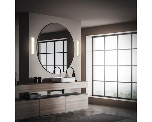 Modernt badrum med stor spegel, tvättställ och fönster.