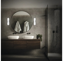 Modernt badrum med dubbla handfat, rund spegel och dusch