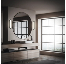 Badrum med tvättställ, rund spegel och stort fönster