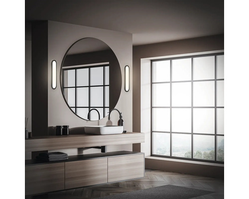 Badrum med tvättställ, rund spegel och stort fönster