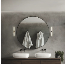 Modernt badrum med dubbla handfat, rund spegel, vägglampor och badrockar