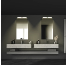 Badrum med två handfat, speglar, handdukar och hyllor i mörka toner.