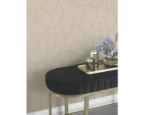 En vägg med mönstrad tapet bakom en bänk med blommor och glas