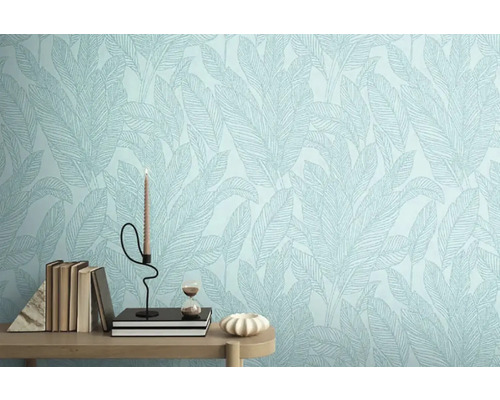 Närbild av en vägg med blad mönstrad tapet, dekorerad med böcker, ljus och timglas