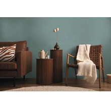 Vardagsrum med brun lädersoffa, träbord, rottingfåtölj och dekoration