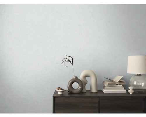 Dekorativ byrå med vaser, böcker och lampa framför en ljus vägg