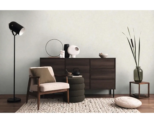 Vardagsrum med fåtölj, byrå, golvlampa och dekoration för en mysig atmosfär.