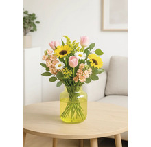 Blombukett med solrosor, tulpaner och prästkragar i vas på bord