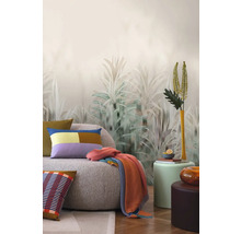 Inredningsidé med en soffa, kuddar, filt och dekorativ väggtapet med växtmotiv.