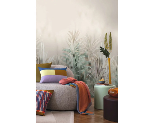 Inredningsidé med en soffa, kuddar, filt och dekorativ väggtapet med växtmotiv.