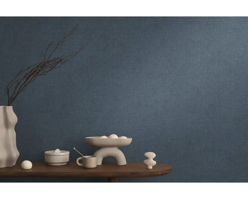 Blå non-woven tapet i vardagsrum med dekoration på ett träbord.