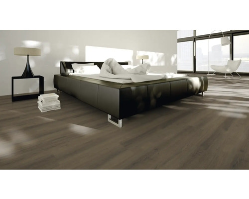 Sovrum med laminatgolv, säng och sänglampa.