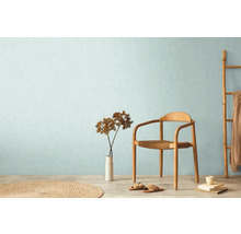 Ljust rum med stol, vas, dekoration och rund matta för en hemtrevlig atmosfär.