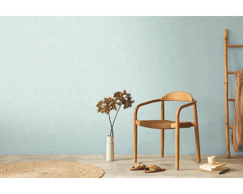 Ljust rum med stol, vas, dekoration och rund matta för en hemtrevlig atmosfär.